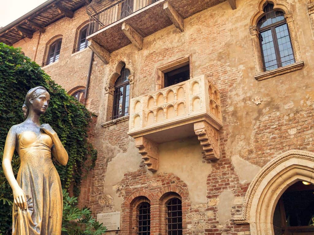 A bronze statue of Juliet stands in a courtyard beneath her balcony in Verona, Italy.