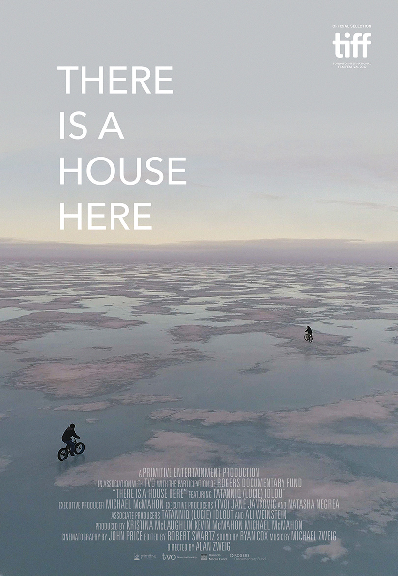 Official poster for There Is A House Here: two cyclists ride across a vast, pink-tinted expanse of melting sea ice beneath a pale sky.