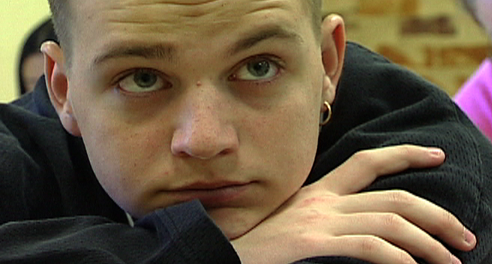 Close-up of a thoughtful young man resting his chin on his folded arms.